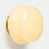 Cream opal glass wall sconce with brass backplate on white wall