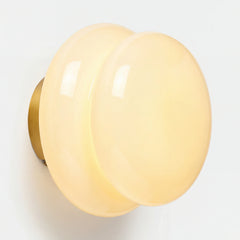 Cream opal glass wall sconce with brass backplate on white wall