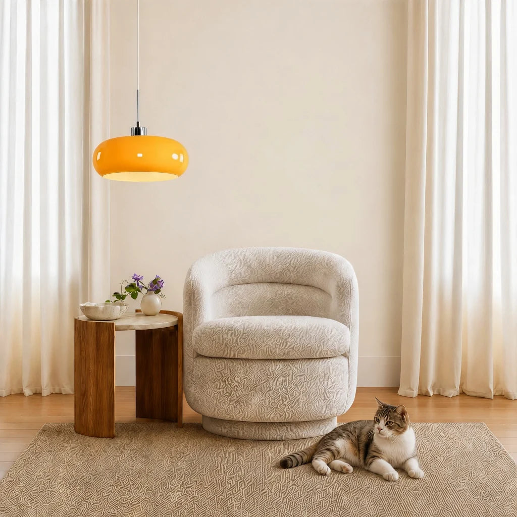 Orange glass pendant light over a boucle armchair with a cat resting nearby