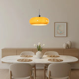 Single orange glass pendant light above an oval marble dining table