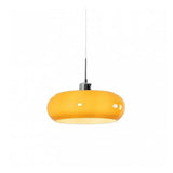 Orange glass pendant light on a thin cord photographed on a white background