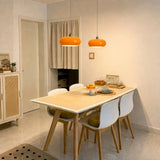Two orange glass pendant lights above a dining table with white chairs