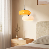 Two orange glass pendant lights beside a mirror above a white dressing table