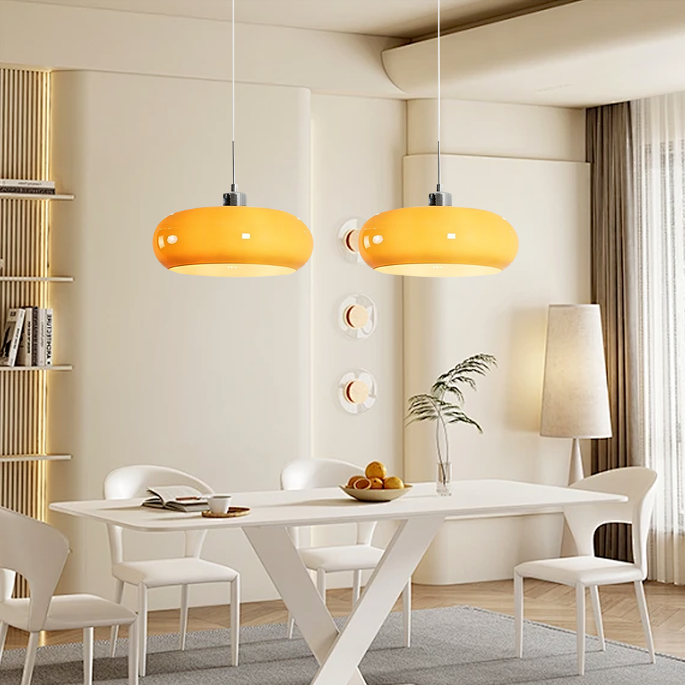 Two orange glass pendant lights hanging in a bright modern dining room