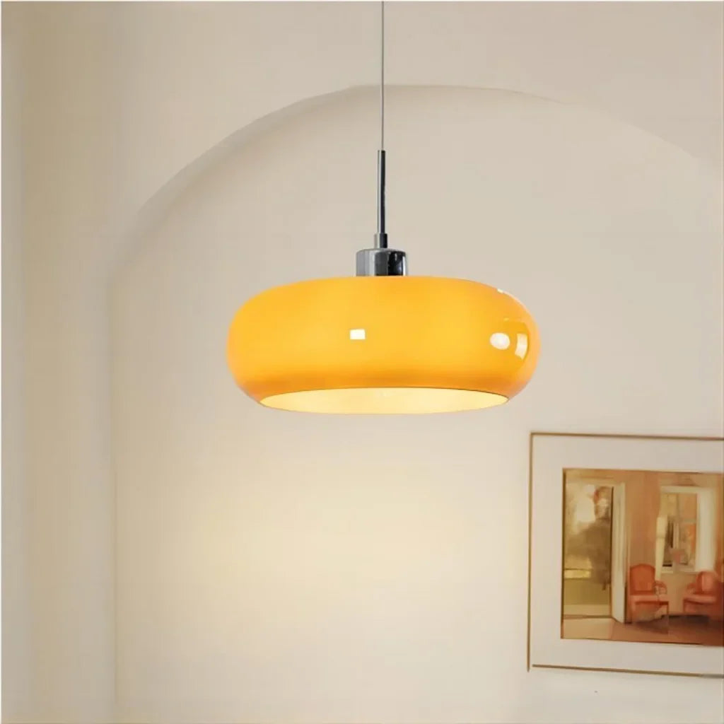 Orange lit glass pendant light against an arched wall with framed art