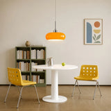 Orange lit glass pendant light over a white table by a bookshelf