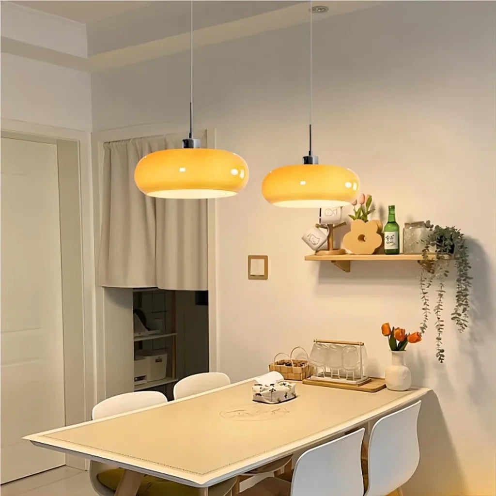 Two orange lit pendant lights in a dining room with shelf decor