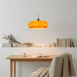 Orange and white glass pendant lights stacked above a bedroom nightstand