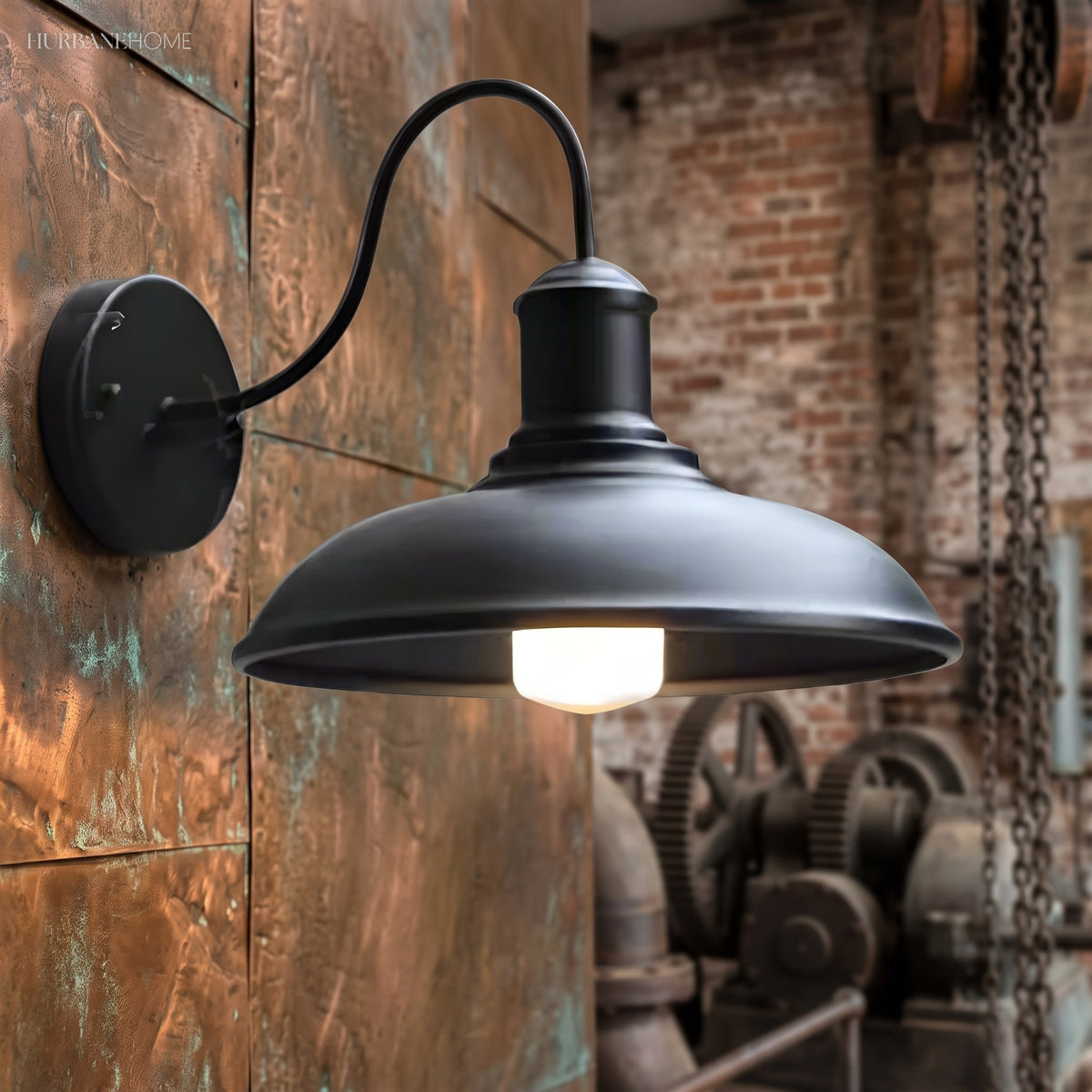 Antique silver gooseneck barn light lit on a rust coloured wall