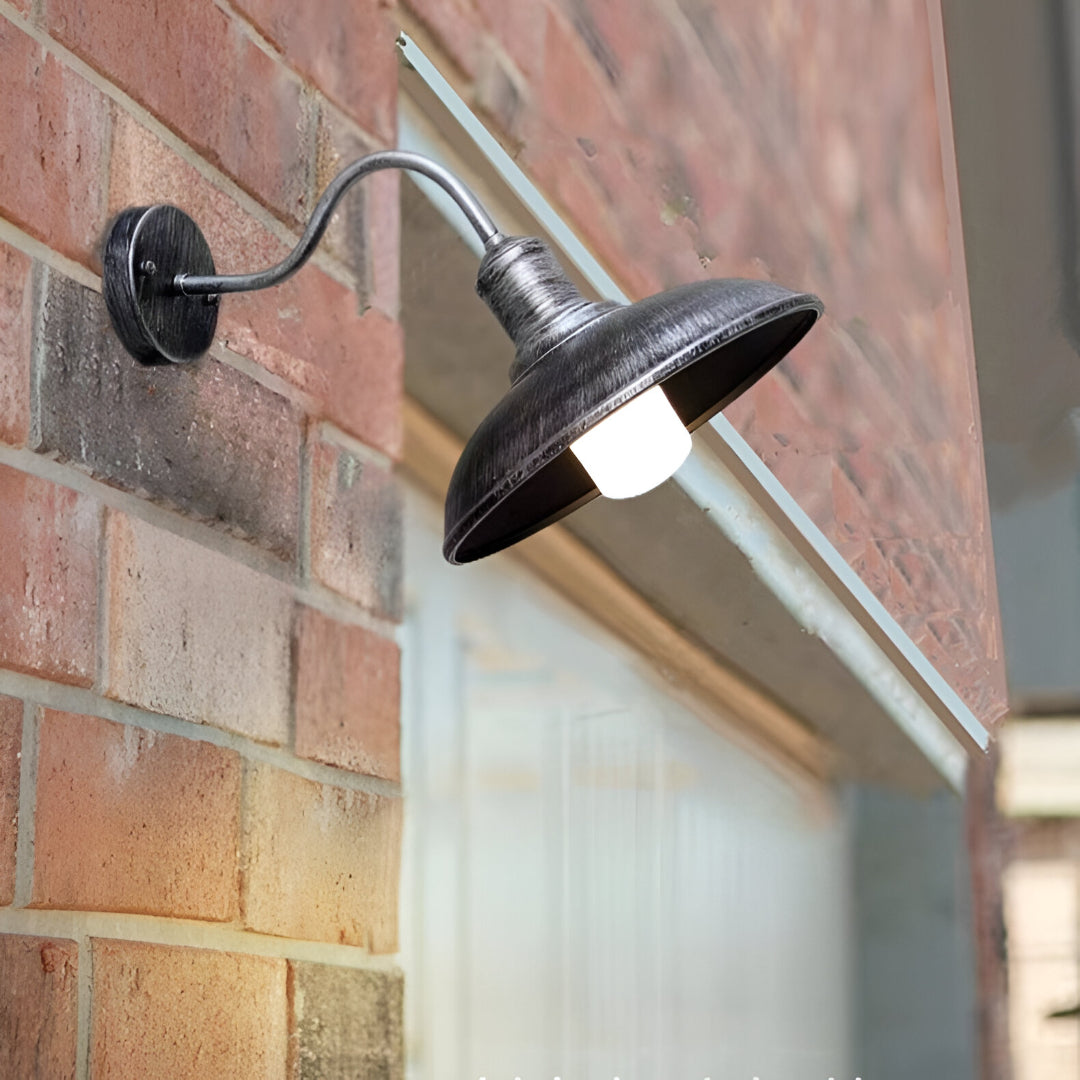 Gooseneck barn light lit on a red brick wall in daylight