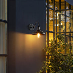 Gooseneck porch light lit on a dark facade beside a lit window