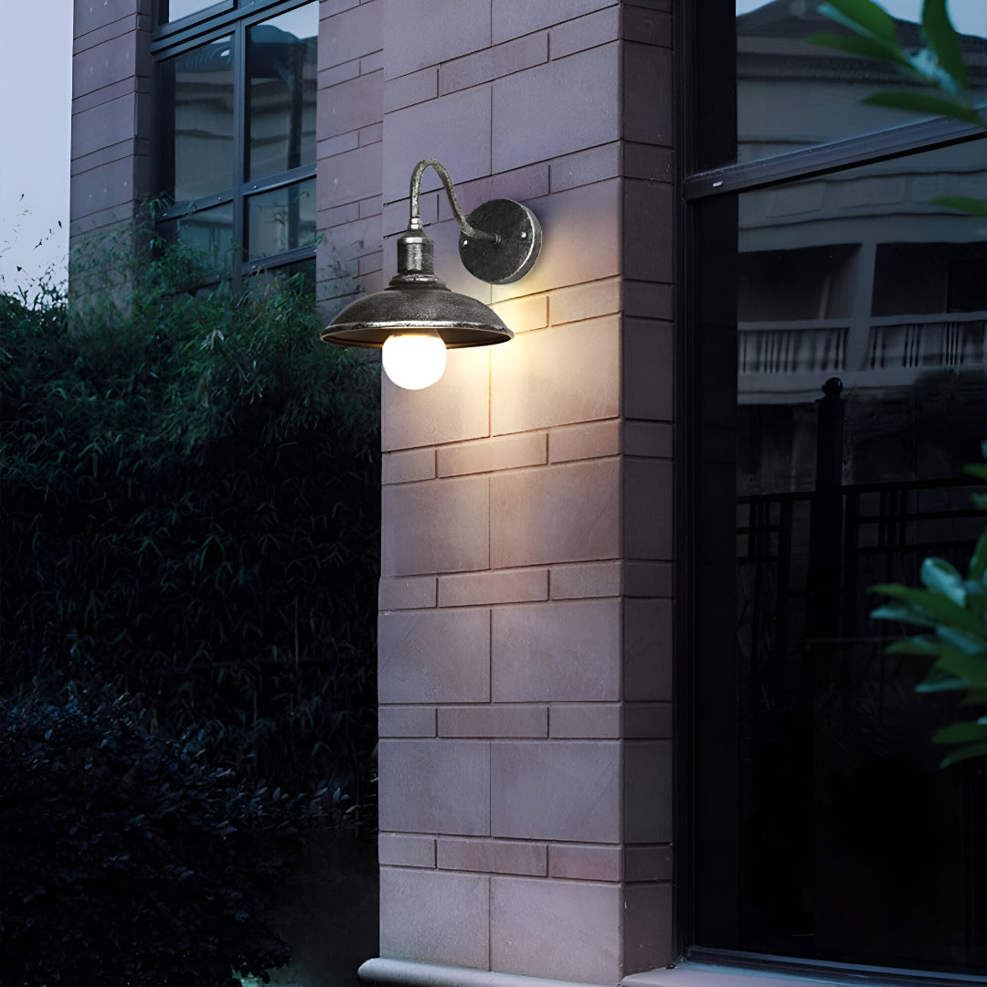 Gooseneck barn light lit on a pale stone column at night