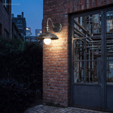 Gooseneck porch light lit at dusk beside a blue industrial door