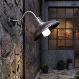 Gooseneck barn light lit on stone beside a black framed window