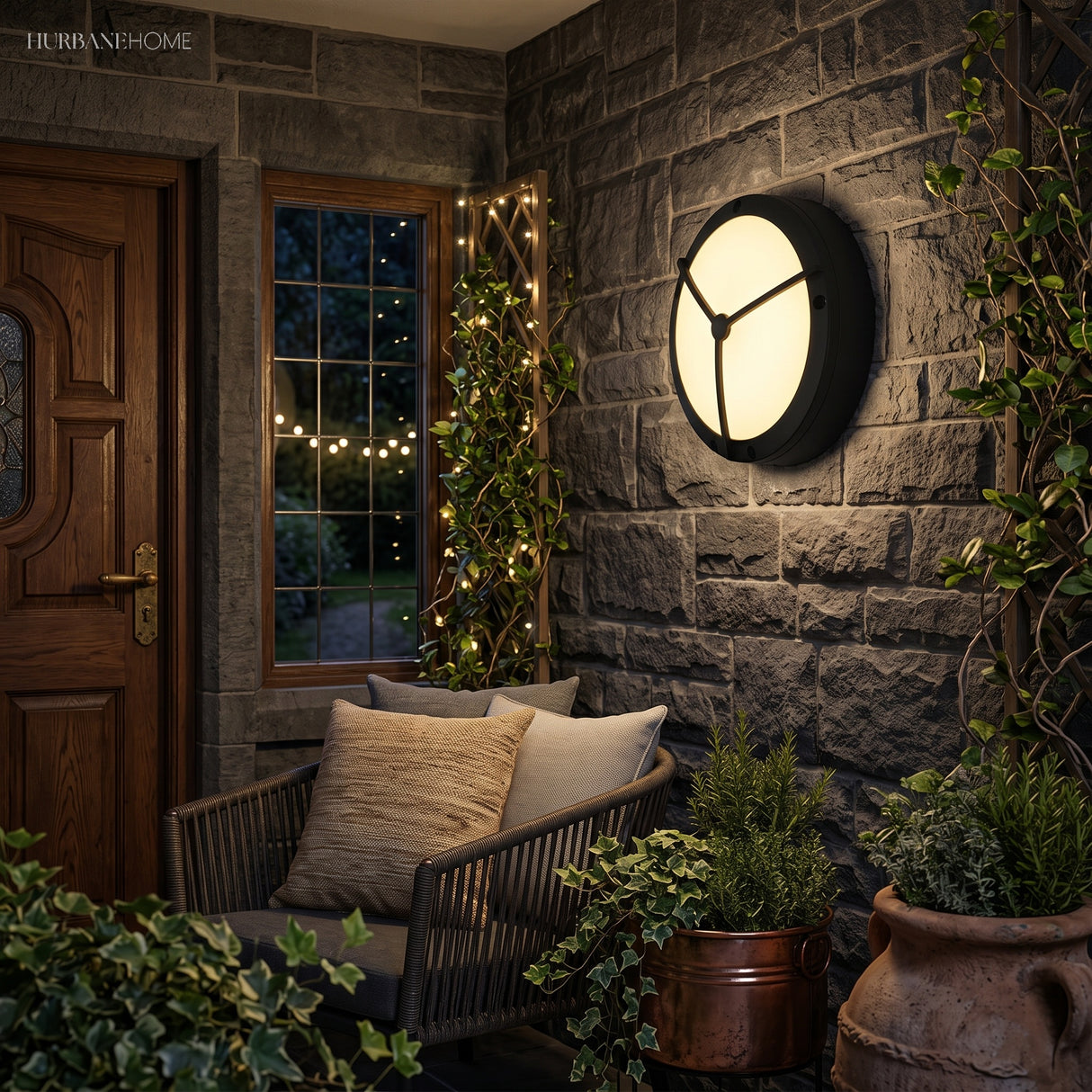 Circular bulkhead light mounted on a garden wall among leafy planting