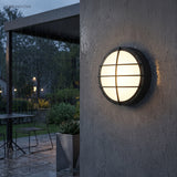 Round porch light with crossed grille beside a timber front door