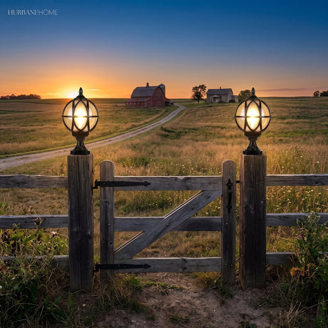 Caged globe post light glowing on a timber fence post at dusk