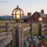 Pair of caged post lights on white columns beside a picket fence
