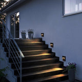 Step lights beside a staircase and handrail on a blue house wall