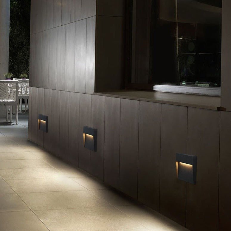 Three step lights along a dark cabinet wall above a pale floor