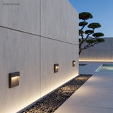 Three step lights washing a pale concrete wall beside a pool