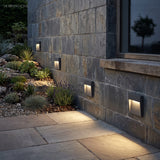 Step lights set into a stone wall above a paved path