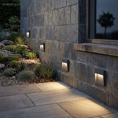 Step lights set into a stone wall above a paved path