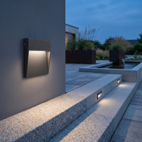 Square black step light washing a stone stair tread at dusk