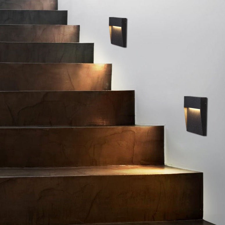 Step lights down rust coloured stone stairs against a white wall