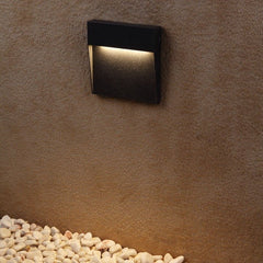 Step light on a rust coloured wall above white pebbles