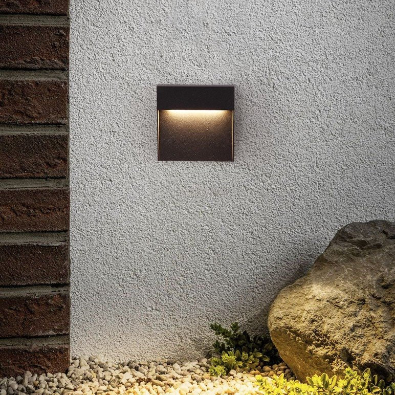Step light on white render beside brickwork and a garden boulder