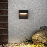 Step light on white render beside brickwork and a garden boulder