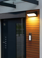 Outdoor light above a numbered entrance door with an intercom panel