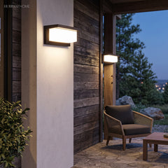 Two outdoor wall lights lit on dark timber cladding at dusk
