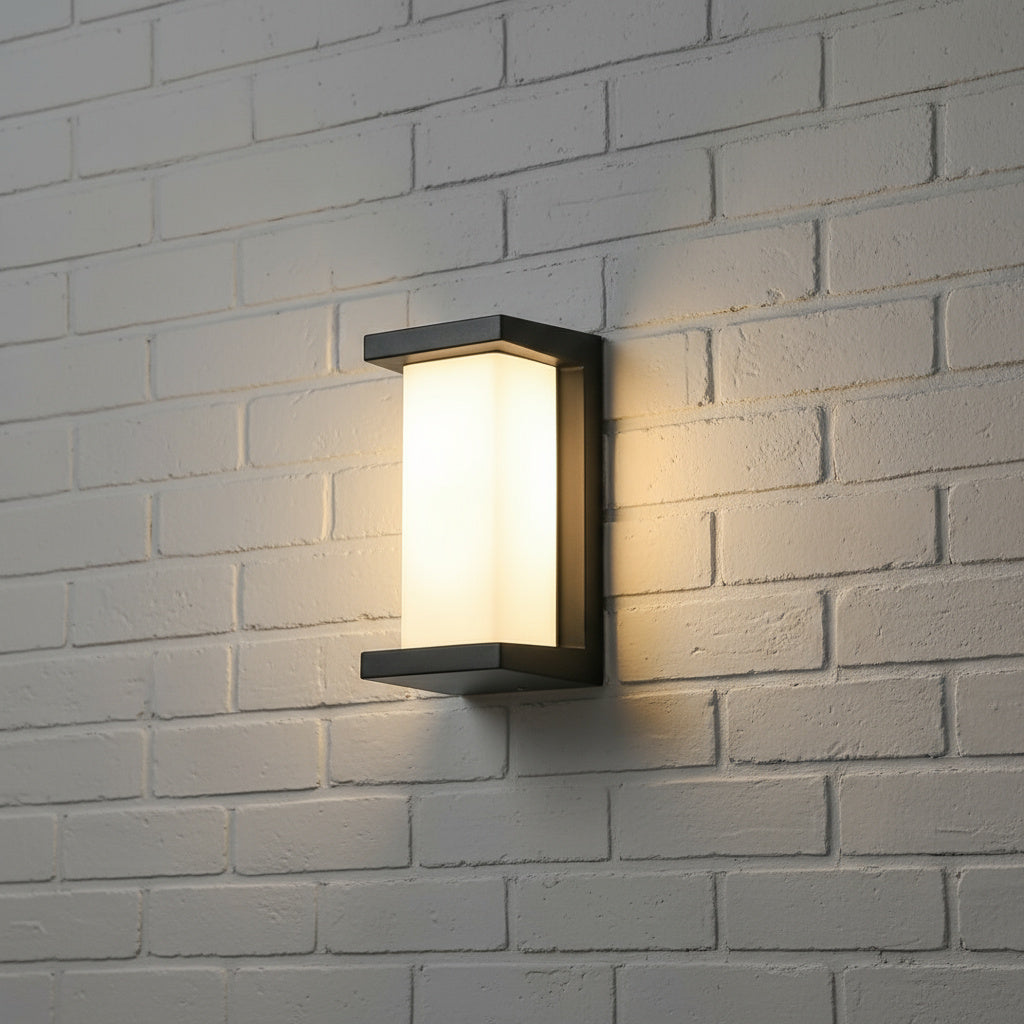 Upright panel outdoor light lit on white painted brick at night