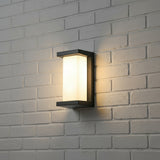 Upright panel outdoor light lit on white painted brick at night