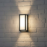 Framed lantern throwing light up and down a white brick wall