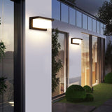 Pair of outdoor lights on a white rendered wall beside tall windows