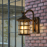 Lantern wall light lit warm on brick beside a garden window