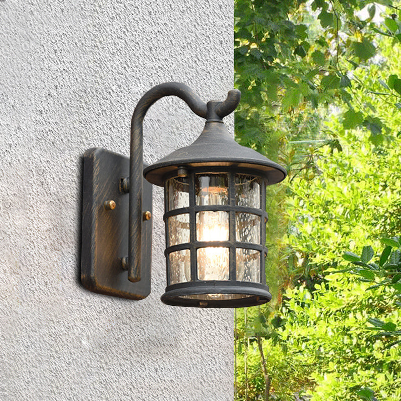 Two lantern wall lights on a rendered wall beside green foliage