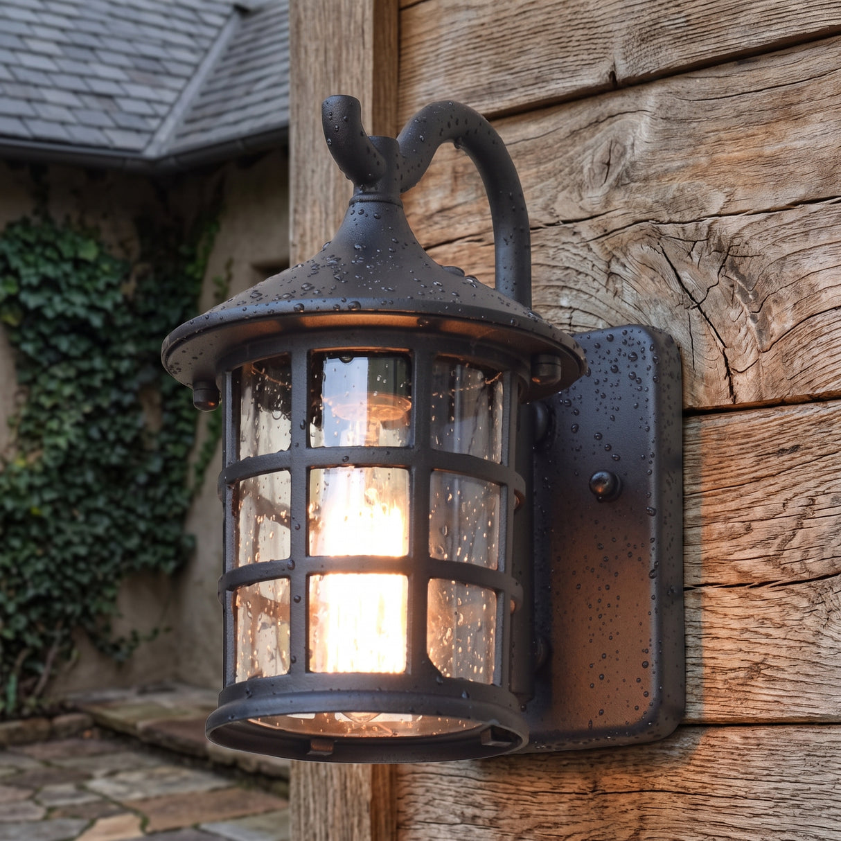 Seeded glass lantern wall light lit on timber under a stone eave