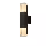 Double head prism wall sconce lit warmly on a pale wall