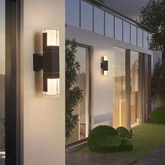 Outdoor wall sconce with a lit clear prism tube on a dark house wall
