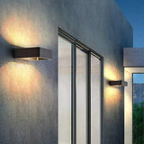 Two outdoor wall sconces lit on a dark wall beside tall glass doors