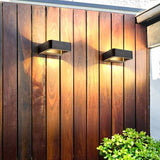 Two outdoor wall sconces lit on a vertical timber clad wall