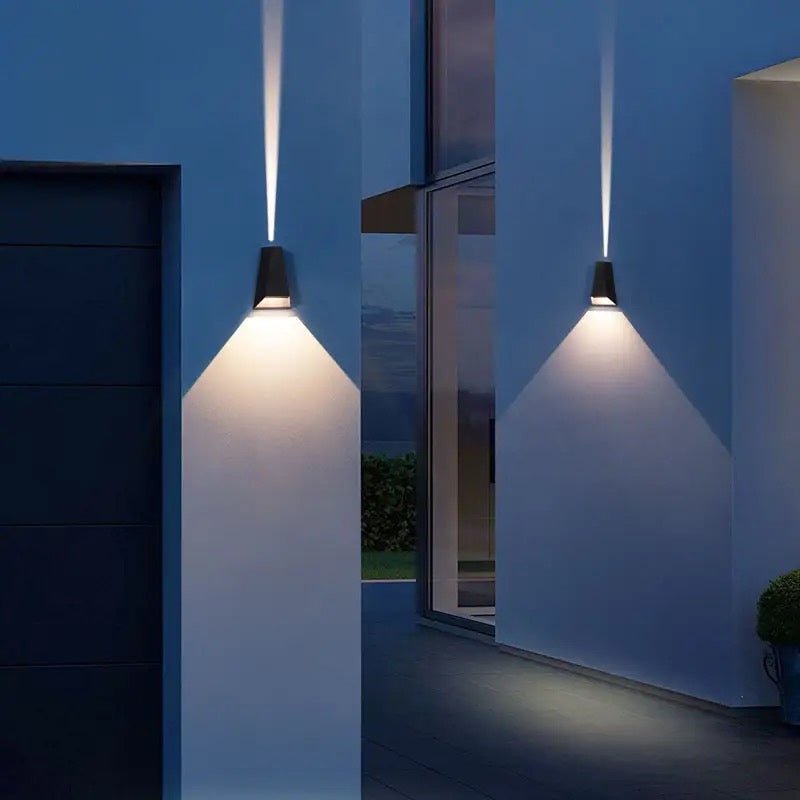 Narrow beams from two sconces on a dark wall by a doorway