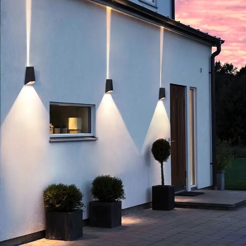 Three sconces lighting a white rendered wall beside a front entrance