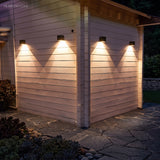 Row of cube sconces lighting a low garden wall and planting