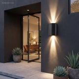 Wall sconce casting narrow beams across a rendered outdoor kitchen wall