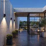 Three wedge sconces washing a concrete wall on a modern patio at dusk